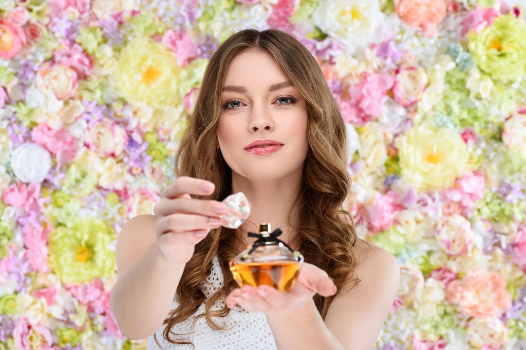 花の背景に香水の美しい若い女性オープニング ボトル - 写真・画像