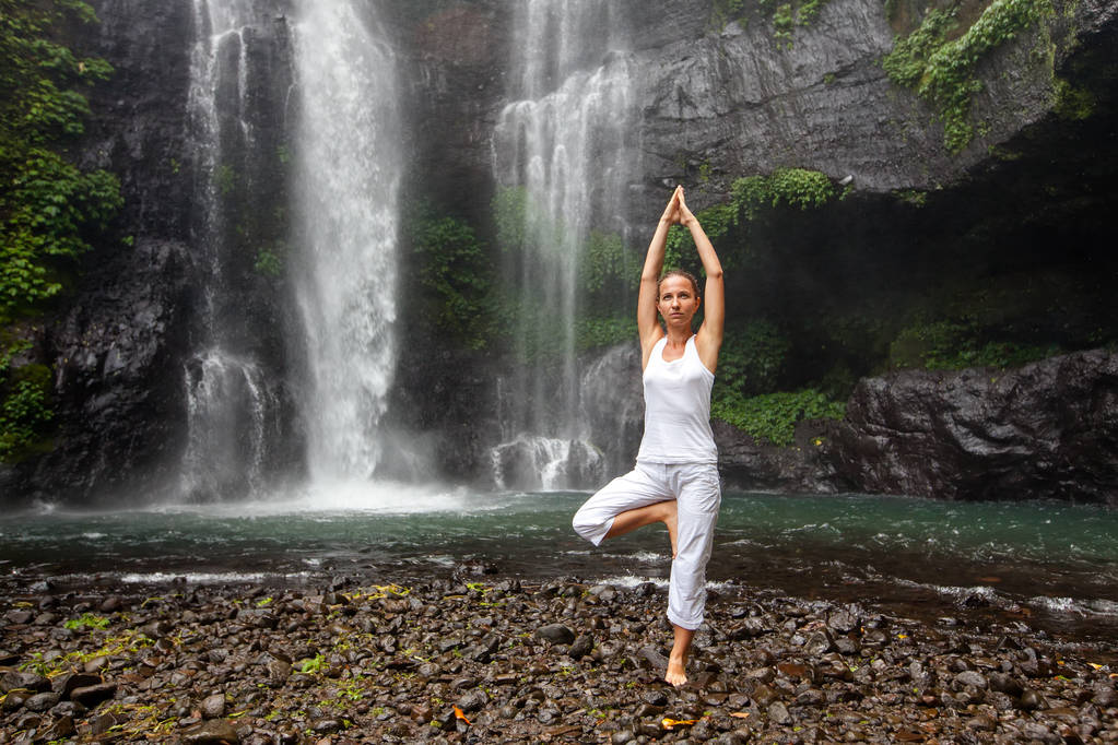 Woman practices yoga near Sekumpul waterfall in Bali, Indonesia - Photo, Image