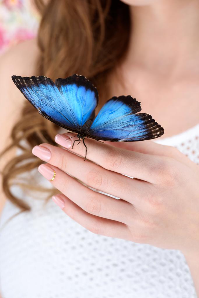 Schnappschuss einer Frau mit blauem Schmetterling an der Hand - Foto, Bild