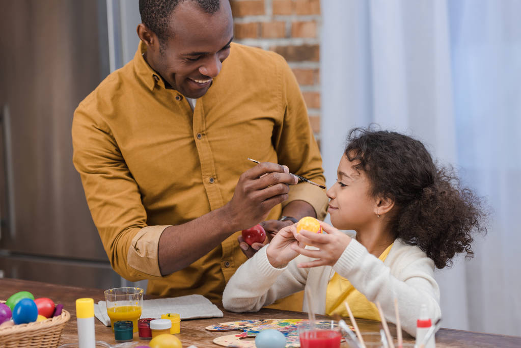 african american father painting daughter nose while painting easter eggs - Photo, Image