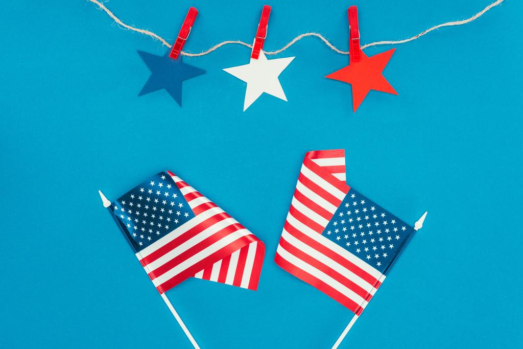 Blick von oben auf arrangierte Sterne und amerikanische Flaggen isoliert auf blauem Grund, Konzept zur Feier des Tages des Präsidenten - Foto, Bild