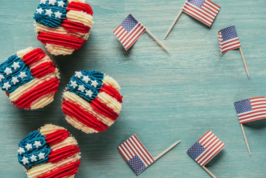 flache Liege mit arrangierten Cupcakes und amerikanischen Flaggen auf hölzerner Tischplatte, Konzept zur Feier des Präsidenten - Foto, Bild