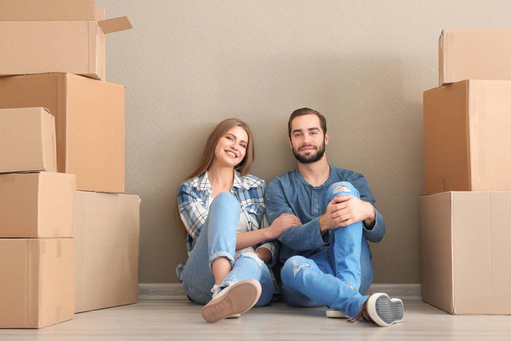 Giovane coppia con scatole mobili al piano in camera
 - Foto, immagini