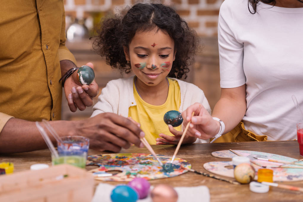 image recadrée de parents afro-américains et de leur fille peignant des œufs de Pâques
 - Photo, image