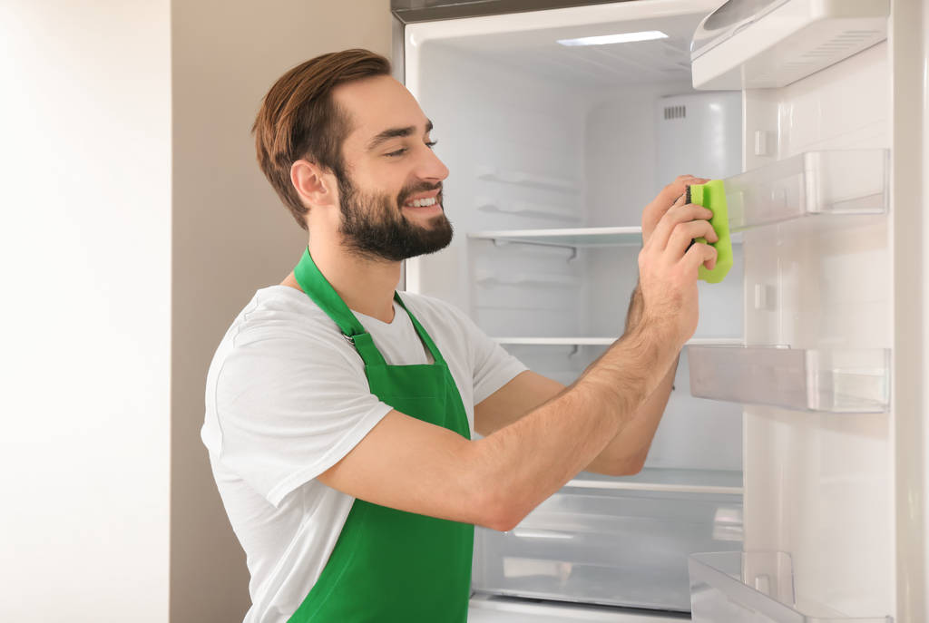Homem de limpeza frigorífico vazio na cozinha
 - Foto, Imagem