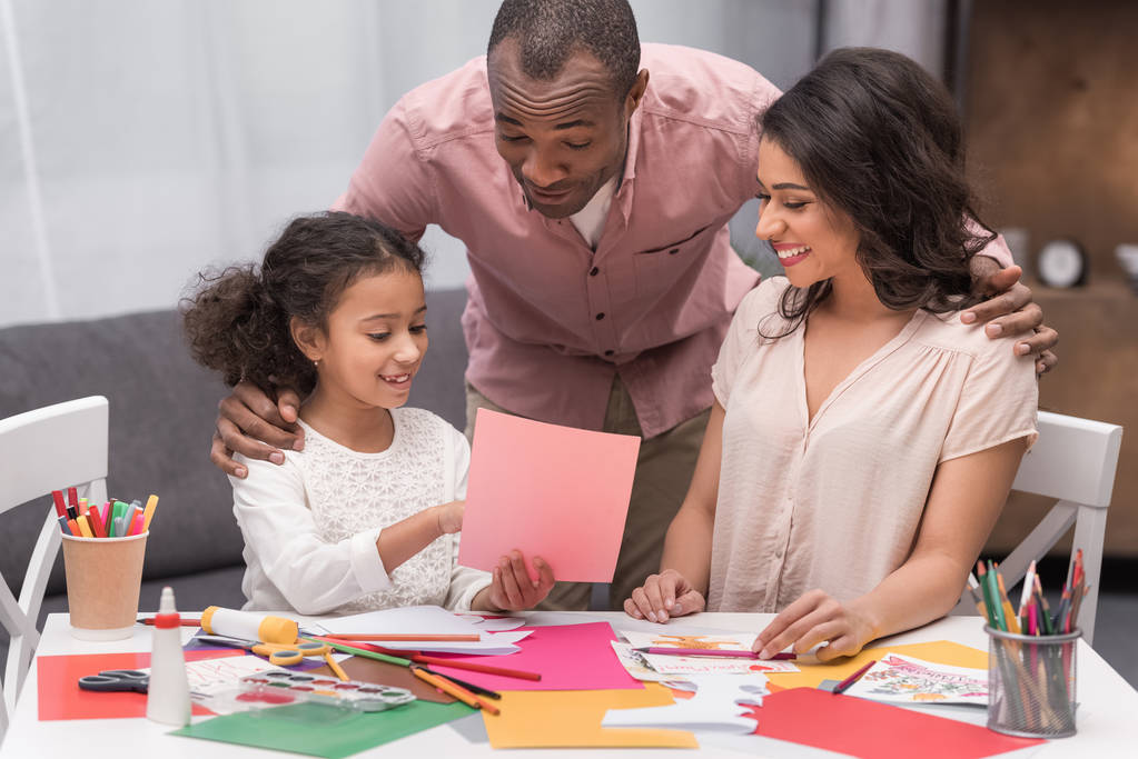 Африканская американская дочь показывает родителям набросок поздравительной открытки на день матери
 - Фото, изображение