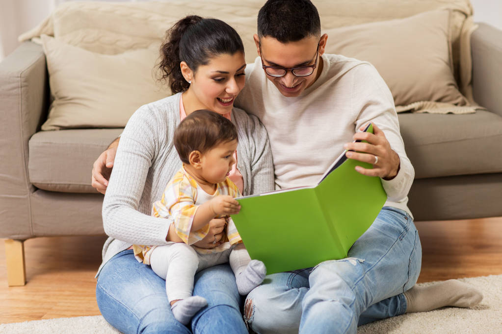 família feliz com livro de leitura do bebê em casa
 - Foto, Imagem