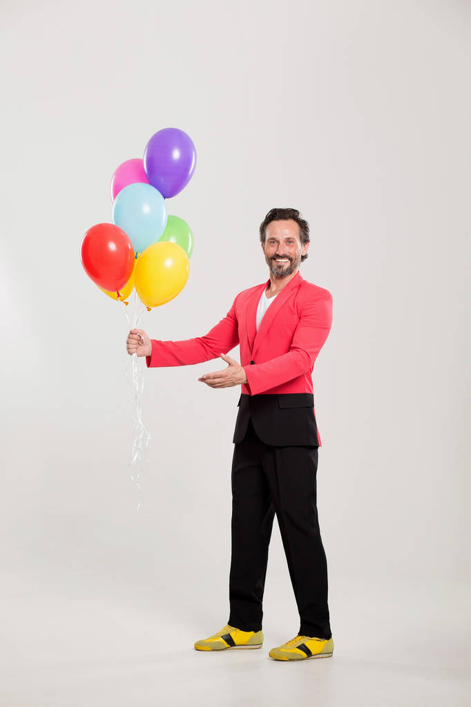 homem de casaco vermelho com balões coloridos
 - Foto, Imagem