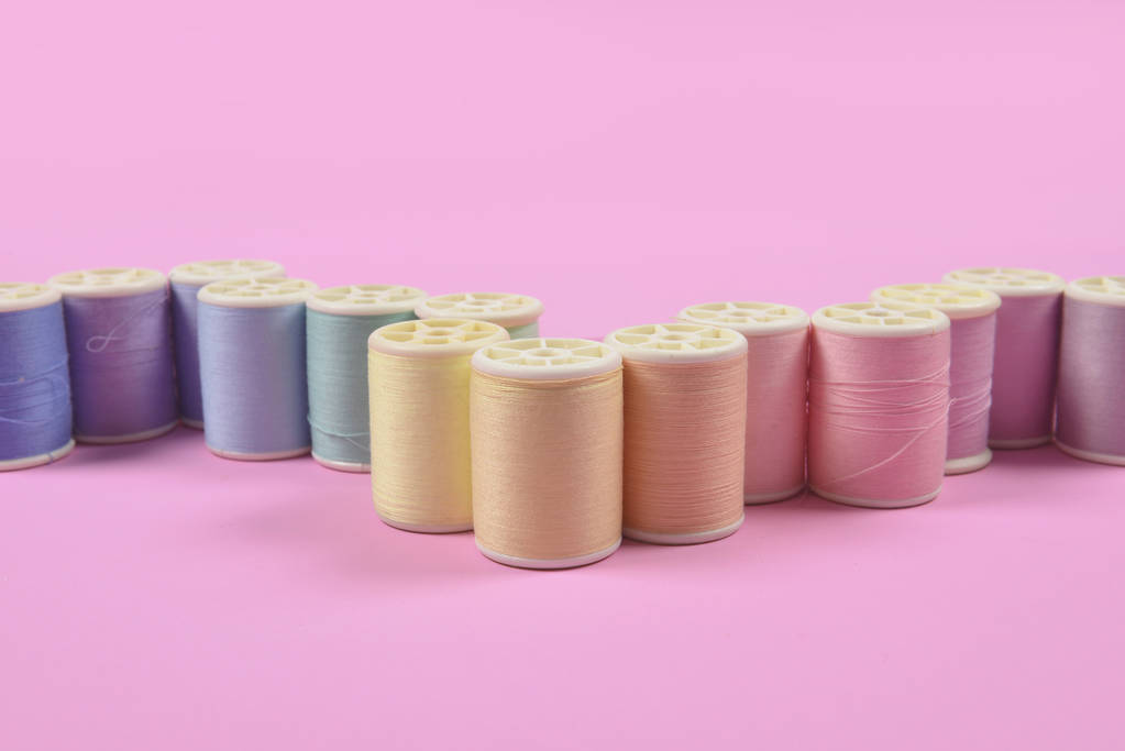 Colocación plana de rollos de hilo de colores para coser sobre fondo rosa
,  - Foto, Imagen
