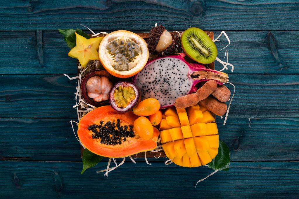 Dragón de frutas, papaya, maracuya, kiwi, mango y granadilla en una caja de madera. Frutas tropicales frescas. Sobre un fondo de madera. Vista superior. Copiar espacio
. - Foto, imagen