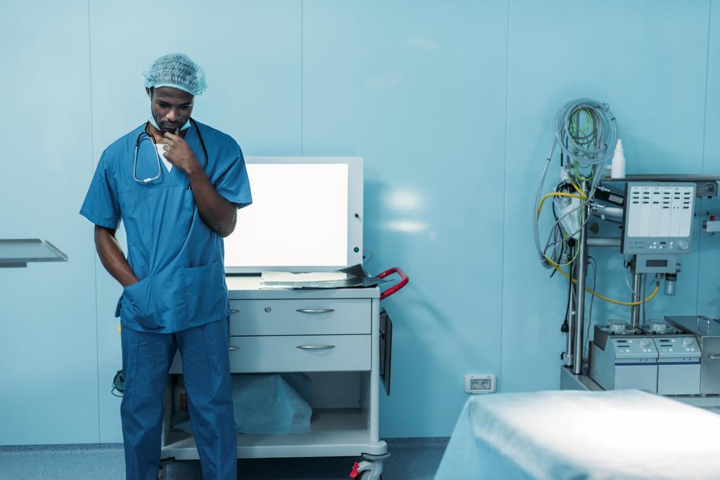 手術室で立っている悲しいのアフリカ系アメリカ人医師 - 写真・画像