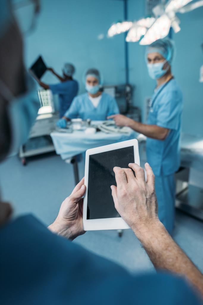 immagine ritagliata del medico utilizzando tablet in sala operatoria
 - Foto, immagini