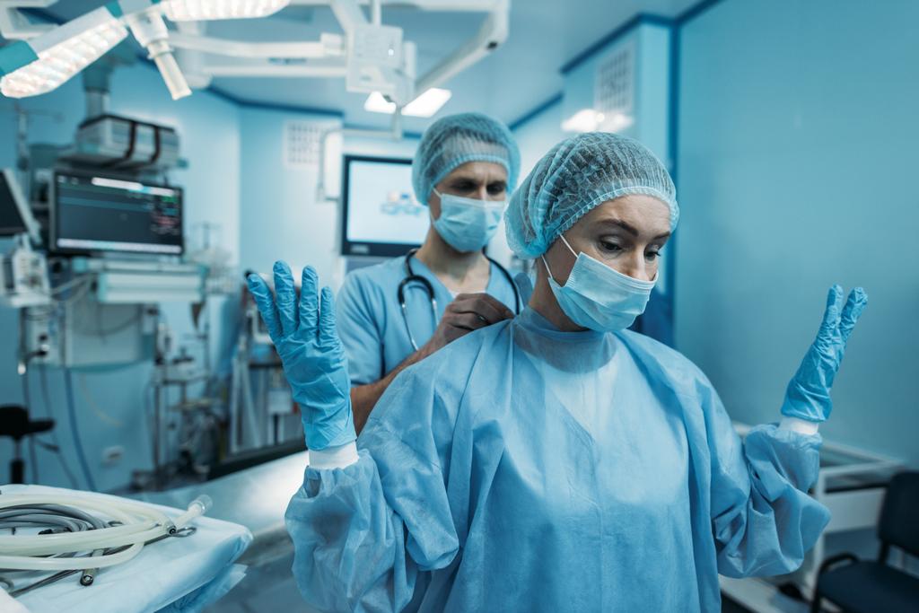 外科医の手術の制服を着用するを助ける医師 ロイヤリティフリー写真 画像素材