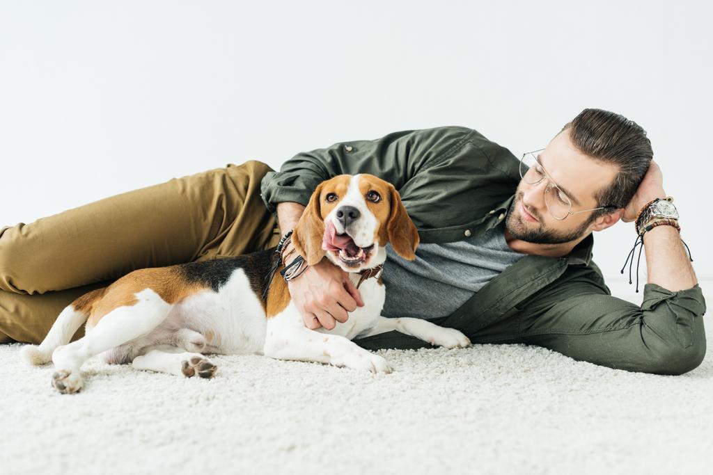 bonito homem deitado no tapete com bonito beagle isolado no branco
 - Foto, Imagem