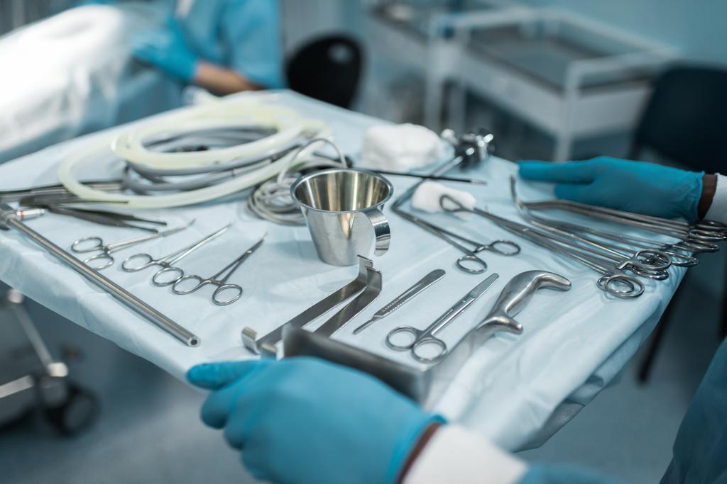 περικομμένη εικόνα του Αφρικανός Αμερικανός γιατρός κρατά θήκη με ιατρικά εργαλεία για τη χειρουργική επέμβαση - Φωτογραφία, εικόνα