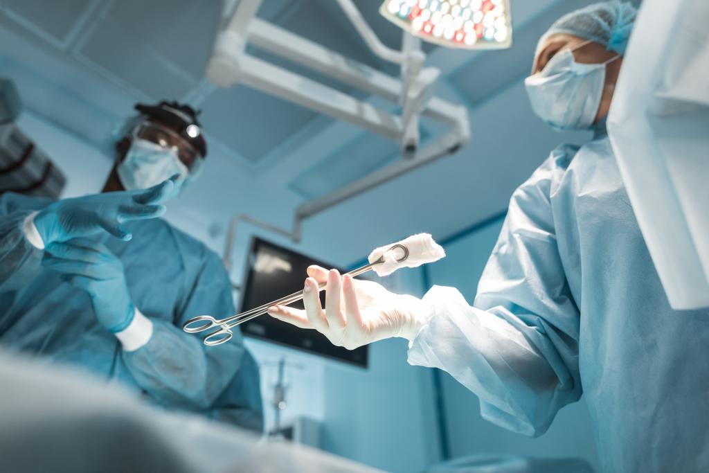 アフリカ系アメリカ人外科医に医療クランプを渡す医者の底面図 - 写真・画像