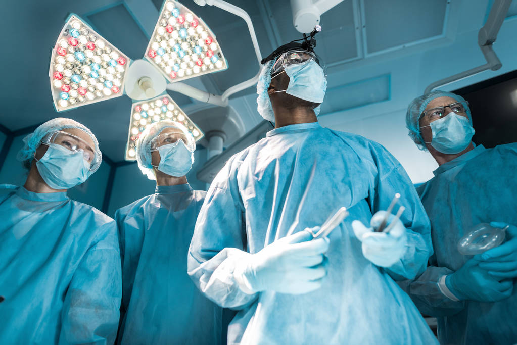 vista inferior de cirujanos multiculturales mirando hacia otro lado
 - Foto, imagen