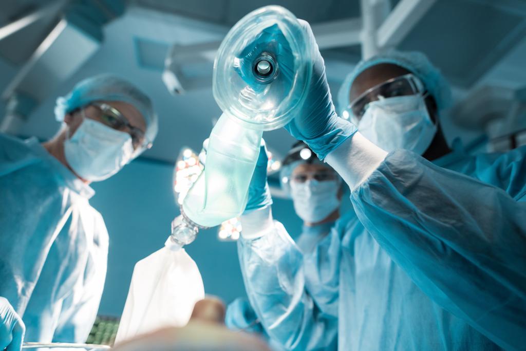 Afro-Amerikan Anestezist oksijen maskesi yukarıda hasta ameliyat odasında tutan alt görünümü - Fotoğraf, Görsel