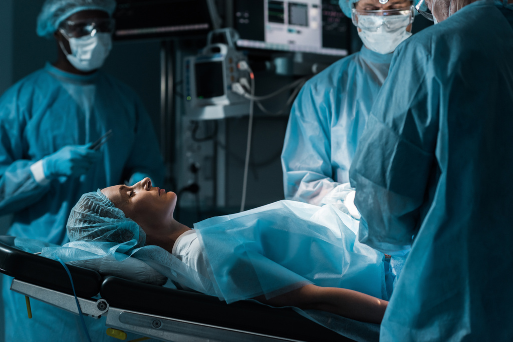 багатоетнічні хірурги і пацієнт в операційній кімнаті
 - Фото, зображення