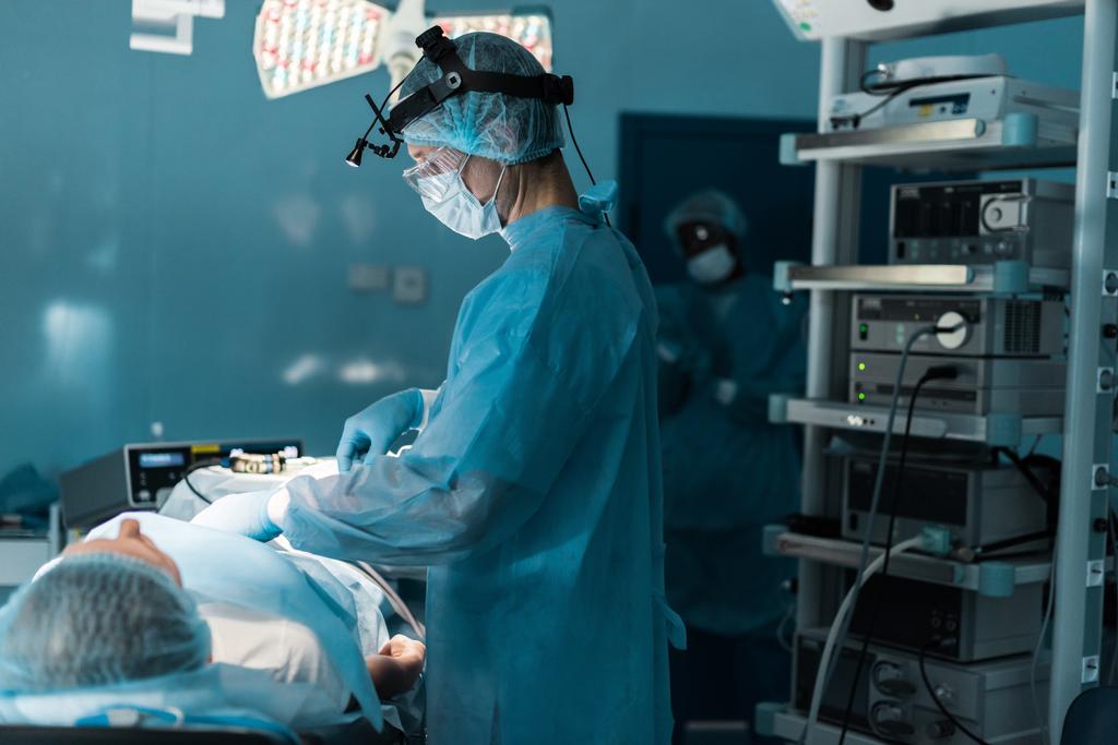 visão lateral do cirurgião operando paciente na sala de cirurgia
 - Foto, Imagem