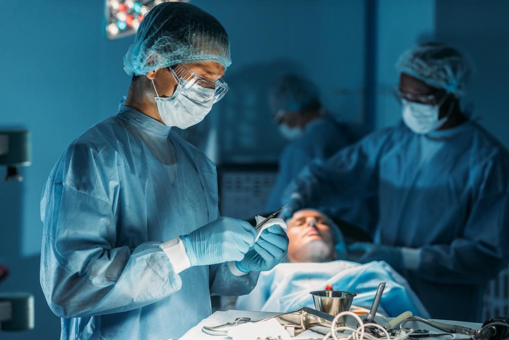 surgeon cleaning scalpel in surgery room - Photo, Image
