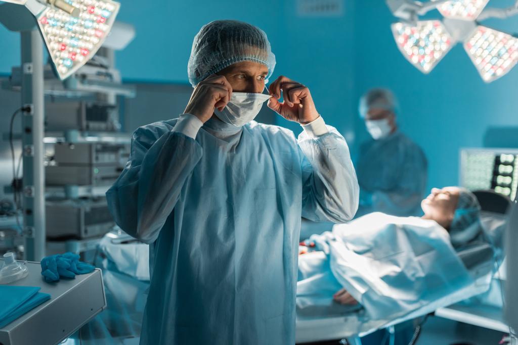 kirurgi, jolla on lääkintänaamio leikkaussalissa
 - Valokuva, kuva