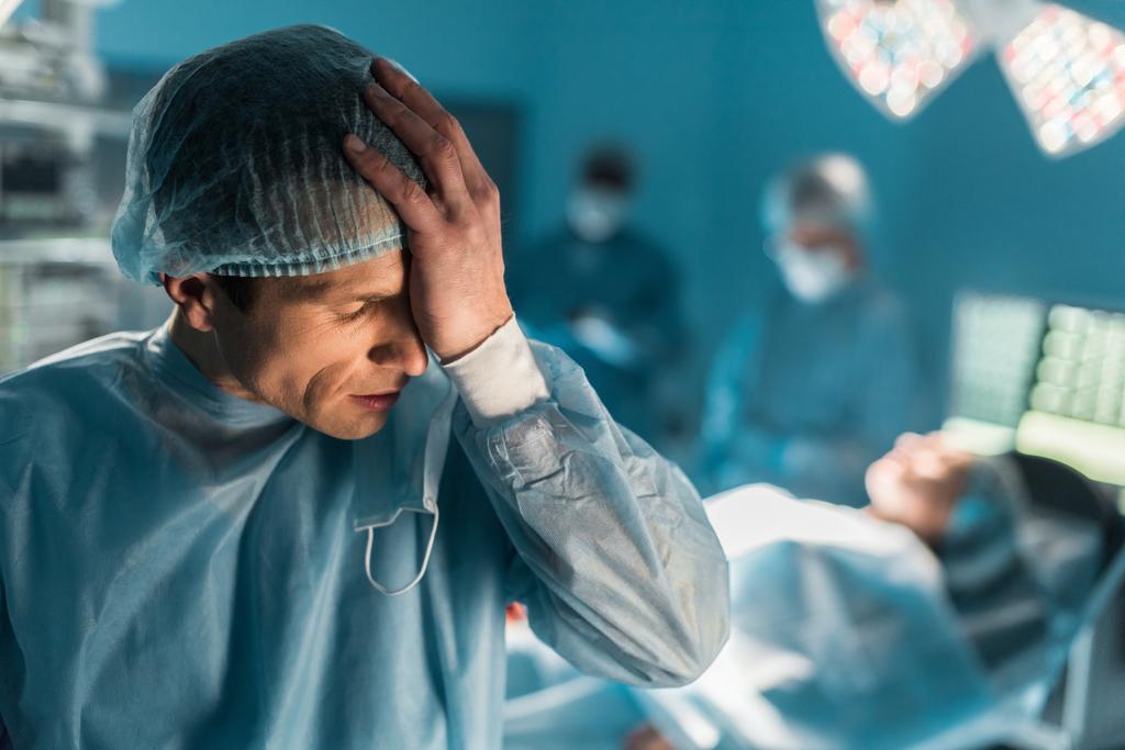 Müder Chirurg berührt Kopf im Operationssaal - Foto, Bild