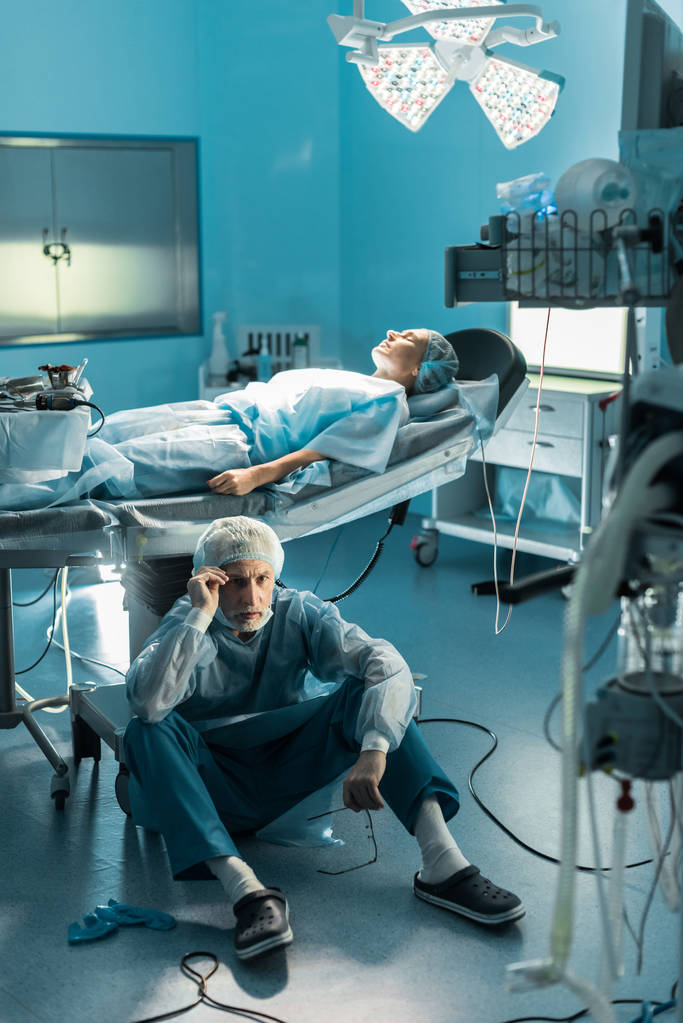 médecin assis sur le sol près du patient sur la table d'opération
 - Photo, image