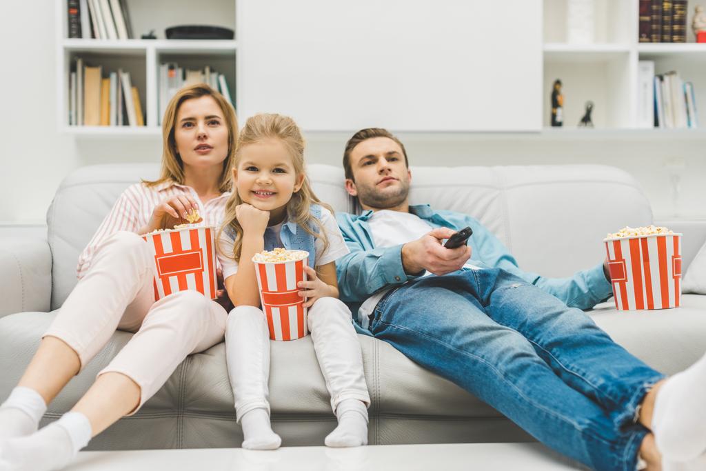 сім'я з попкорном дивиться телевізор разом вдома
 - Фото, зображення
