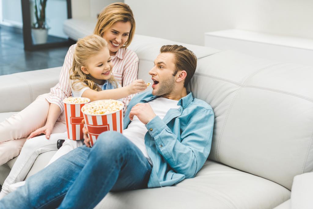 ευτυχισμένη οικογένεια με ποπ κορν βλέποντας την ταινία μαζί στο σπίτι - Φωτογραφία, εικόνα