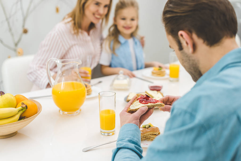 enfoque selectivo del hombre desayunando junto con la familia en casa
 - Foto, imagen