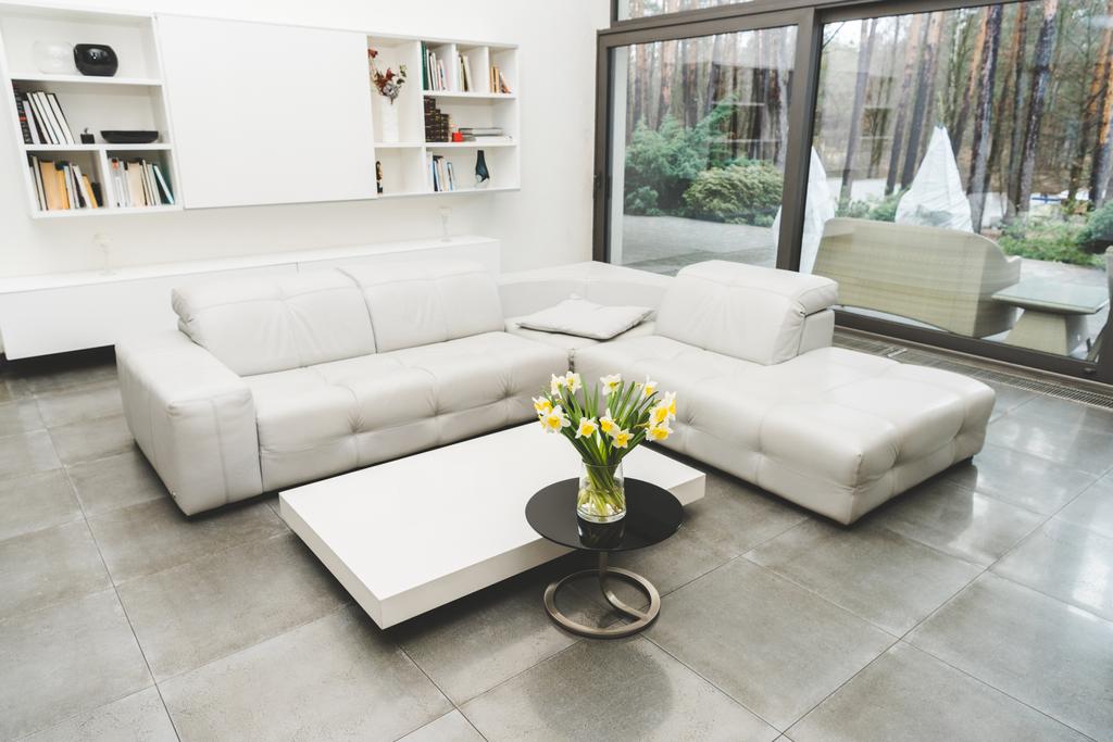 vista da sala de estar vazia com sofá branco e buquê de flores na mesa de café
 - Foto, Imagem