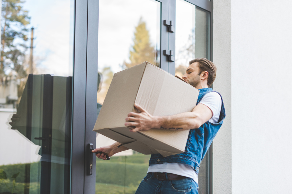 hombre con caja de cartón que abre la puerta de la casa nueva
 - Foto, imagen
