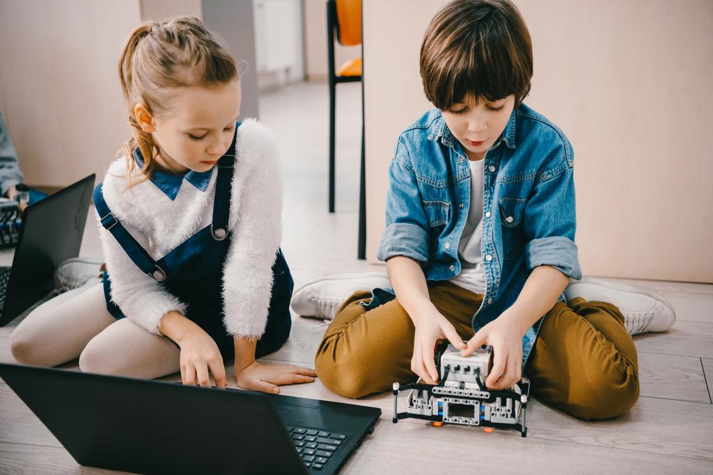 子供クラス機械で床に座ってながらロボットをプログラミングに焦点を当ててください。 - 写真・画像
