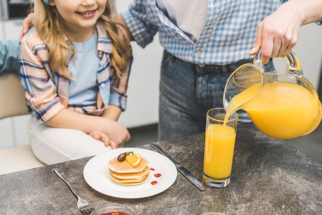 részleges kilátás nyílik ömlött juice pohárba lányával reggeli közben nő - Fotó, kép