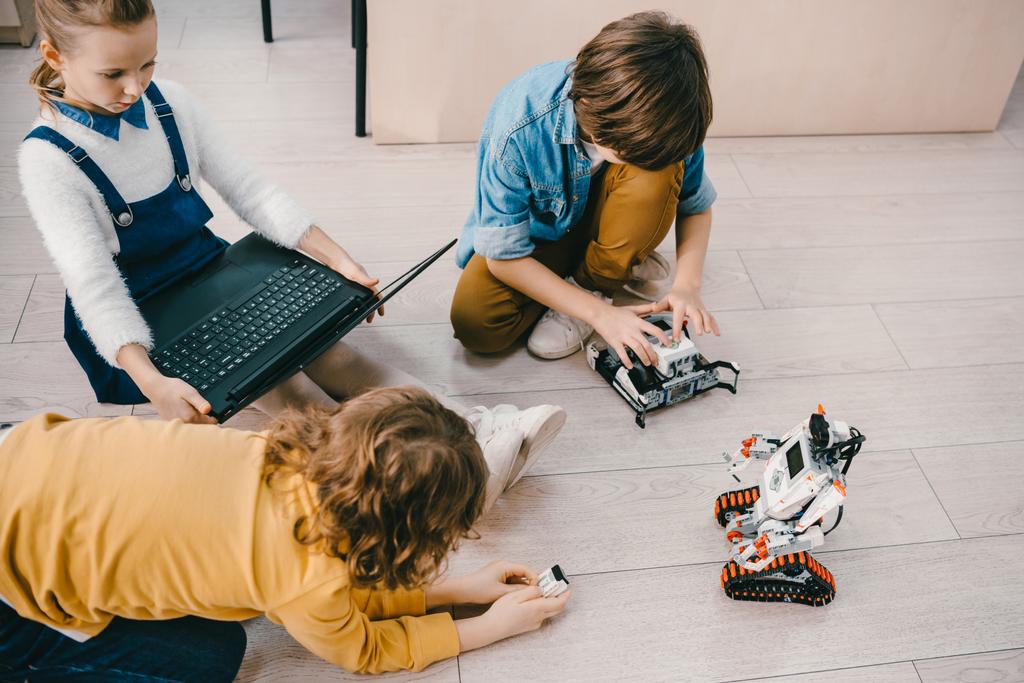 ロボットとラップトップ幹教育クラスの床の上に座って子供たちのハイアングル - 写真・画像