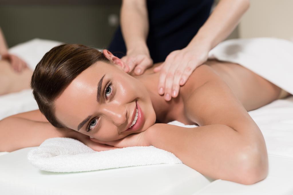 joven mujer sonriendo en cámara mientras teniendo masaje corporal
 - Foto, imagen