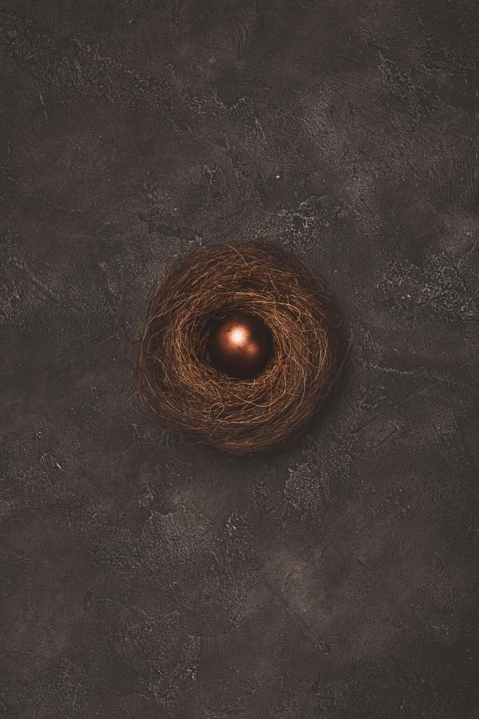 vista dall'alto dell'uovo di Pasqua dorato nel nido sulla superficie di cemento
  - Foto, immagini