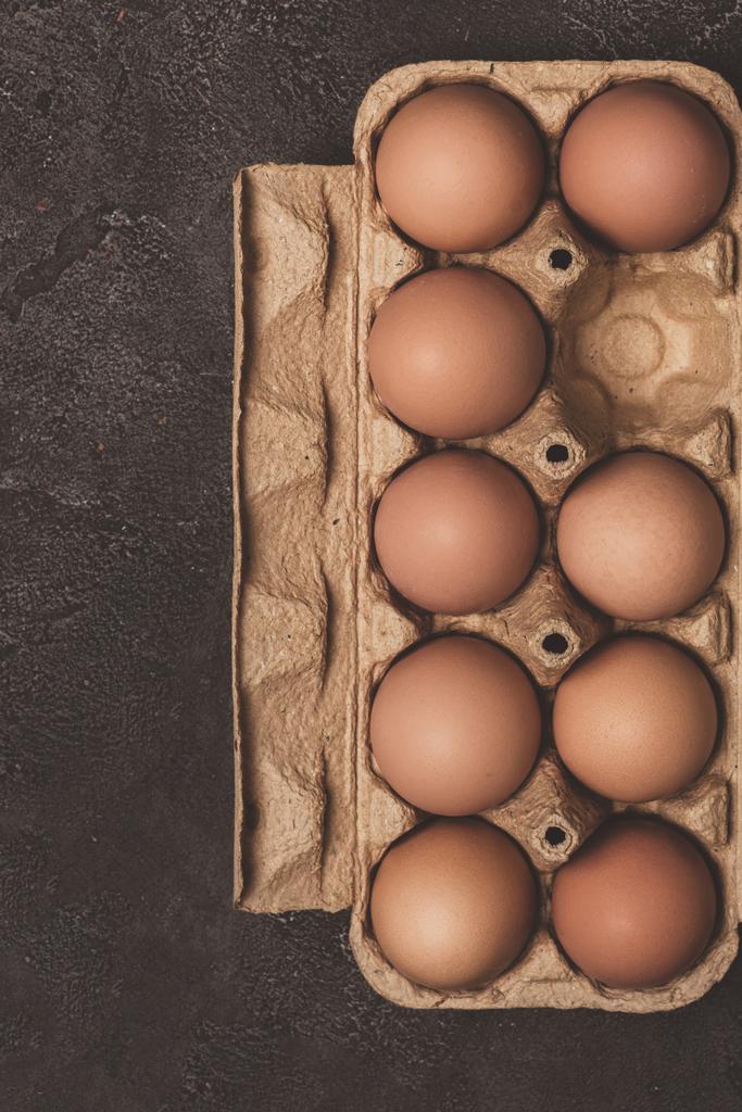 vista superior de huevos de pollo en bandeja de cartón en gris
 - Foto, Imagen