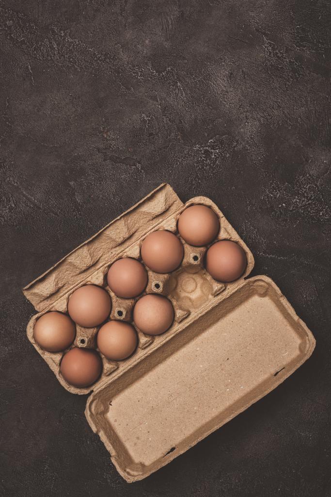 vista superior de huevos de pollo en bandeja de cartón sobre hormigón gris
 - Foto, Imagen
