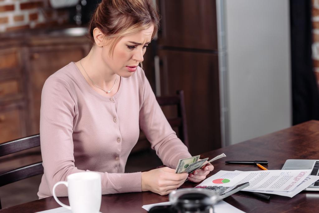 vista laterale della donna sconvolta contando i soldi a tavola a casa, concetto di problemi finanziari
 - Foto, immagini