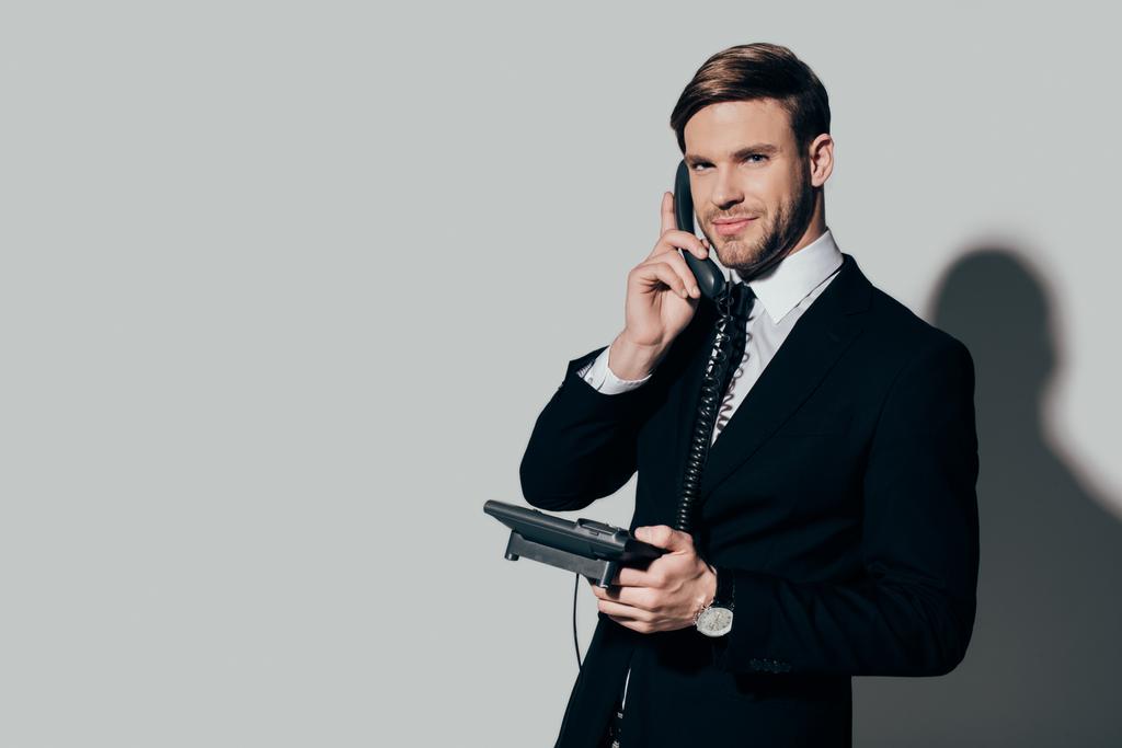 Joven empresario confiado en traje hablando por teléfono sobre fondo blanco
 - Foto, Imagen