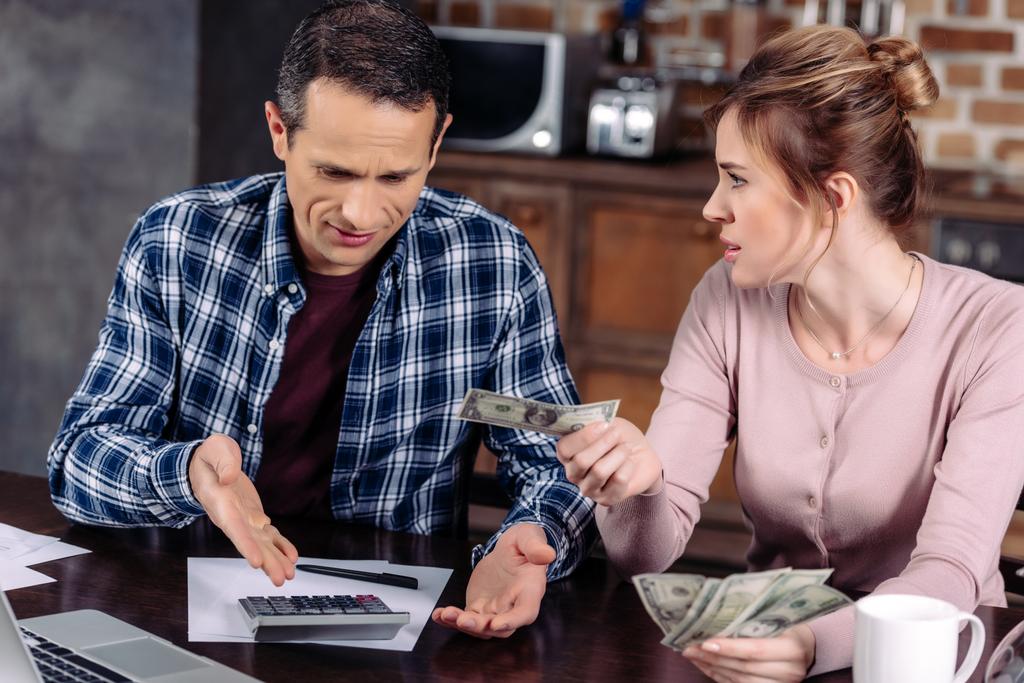 portrait of couple counting money while sitting at table at home, financial problems concept - Photo, Image