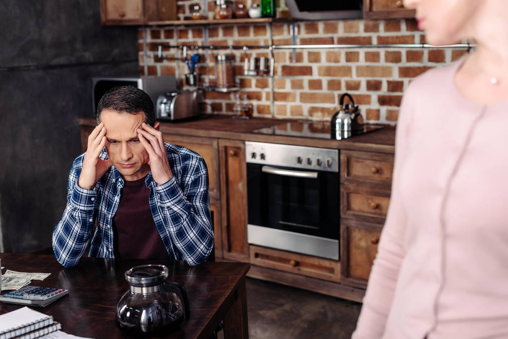 enfoque selectivo de la mujer mirando marido pensativo en la mesa en el hogar, concepto de problemas financieros
 - Foto, imagen