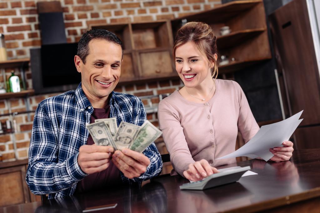 portrait of happy couple counting money together at home - Photo, Image