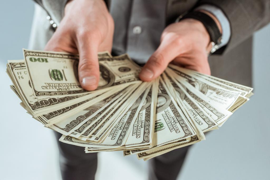 Крупный план бизнесмена, держащего в руках долларовые банкноты
 - Фото, изображение