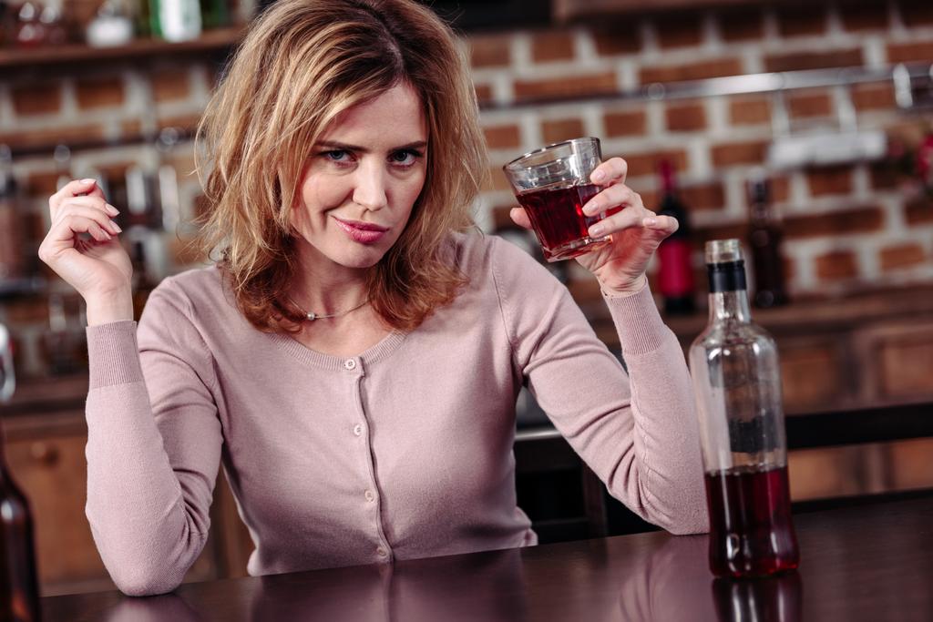 портрет женщины со стаканом алкоголя, смотрящей в камеру дома
 - Фото, изображение