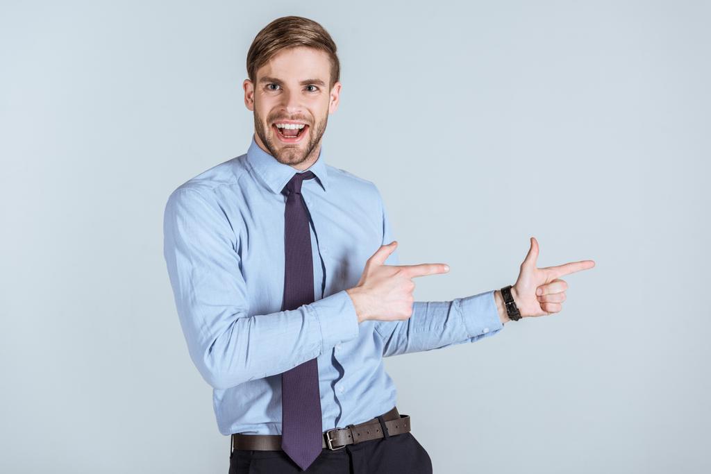 Молодой возбужденный бизнесмен, указывающий на серый
  - Фото, изображение