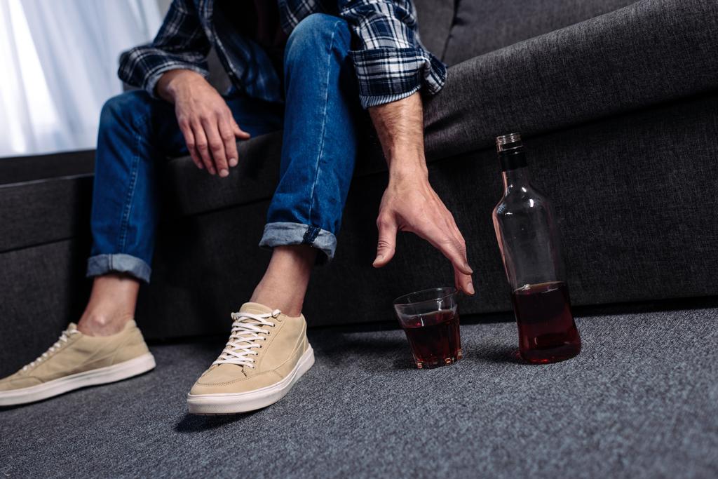 partial view of man taking alcohol drink while sitting on sofa at home - Photo, Image