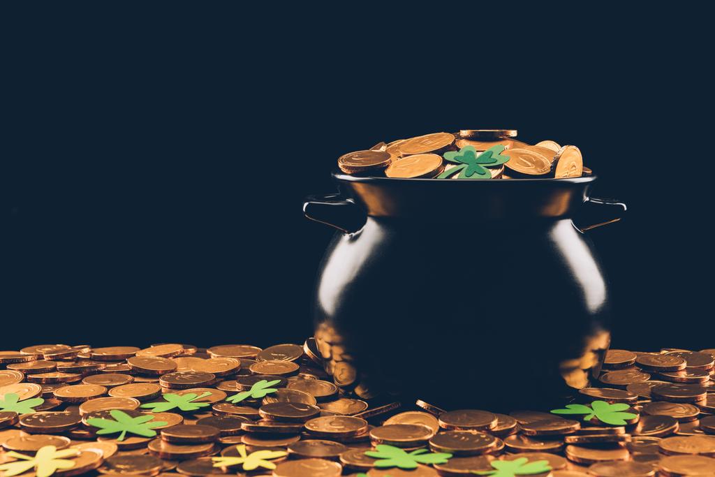 zwarte pot met gouden munten en shamrock geïsoleerd op zwart, st patricks dag concept - Foto, afbeelding